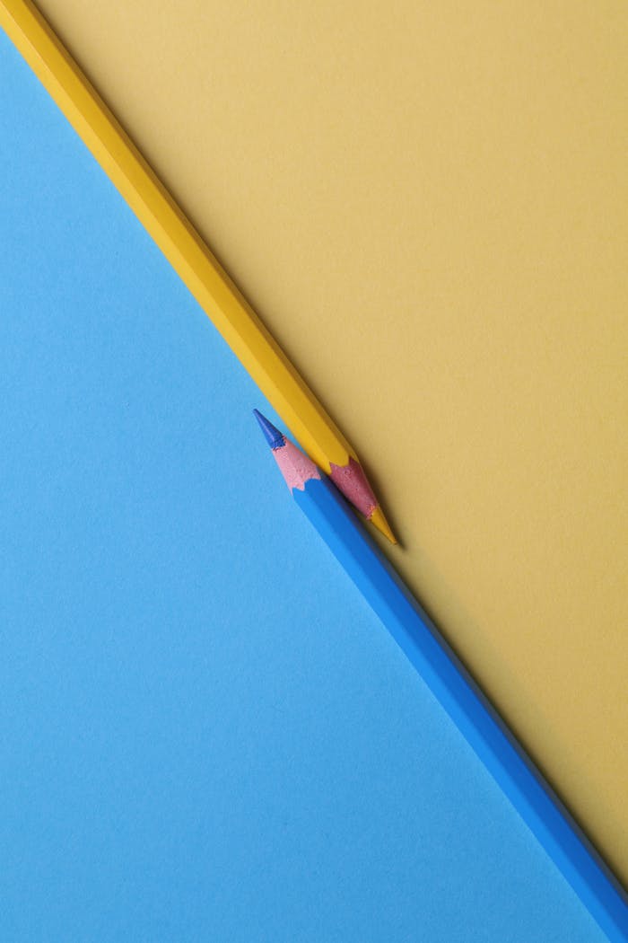 menu-02 Close-up of vibrant yellow and blue colored pencils on contrasting paper backgrounds.